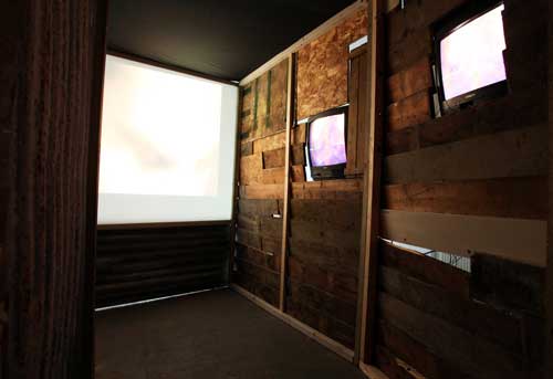 Giorgio Bruni. And What? (inner view), 2010. DVD loop, TVs, projection, wood, corrugated iron, dimensions variable. © the artist.