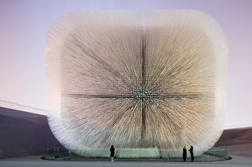 Heatherwick Studio. UK Pavilion, Shanghai Expo 2010. The Seed Cathedral is a box, 15 metres high and 10 metres tall. From every surface protrude silvery hairs, consisting of 60,000 identical rods of clear acrylic, 7.5 metres long, which extend through the walls of the box and lift it into the air. Inside the pavilion, the geometry of the rods forms a space described by a curvaceous undulating surface. There are 250,000 seeds cast into the glassy tips of all the hairs. Photograph: Iwan Baan.