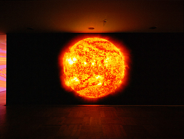 Katharina Sieverding. Die Sonne Um Mitternacht Schauen (Red), 2011-12, Sdo/Nasa. Digital film projection,  500 x 500 cm,  100:00 min, Loop . Courtesy the artist and studio 111a.